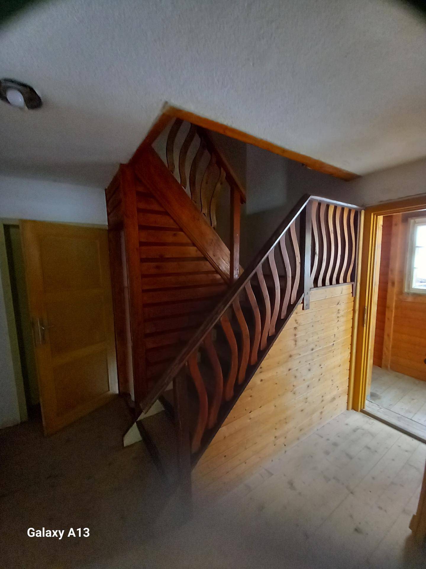 Holztreppe mit kunstvoll geschnitztem Geländer, die zu den oberen Etagen führt.
