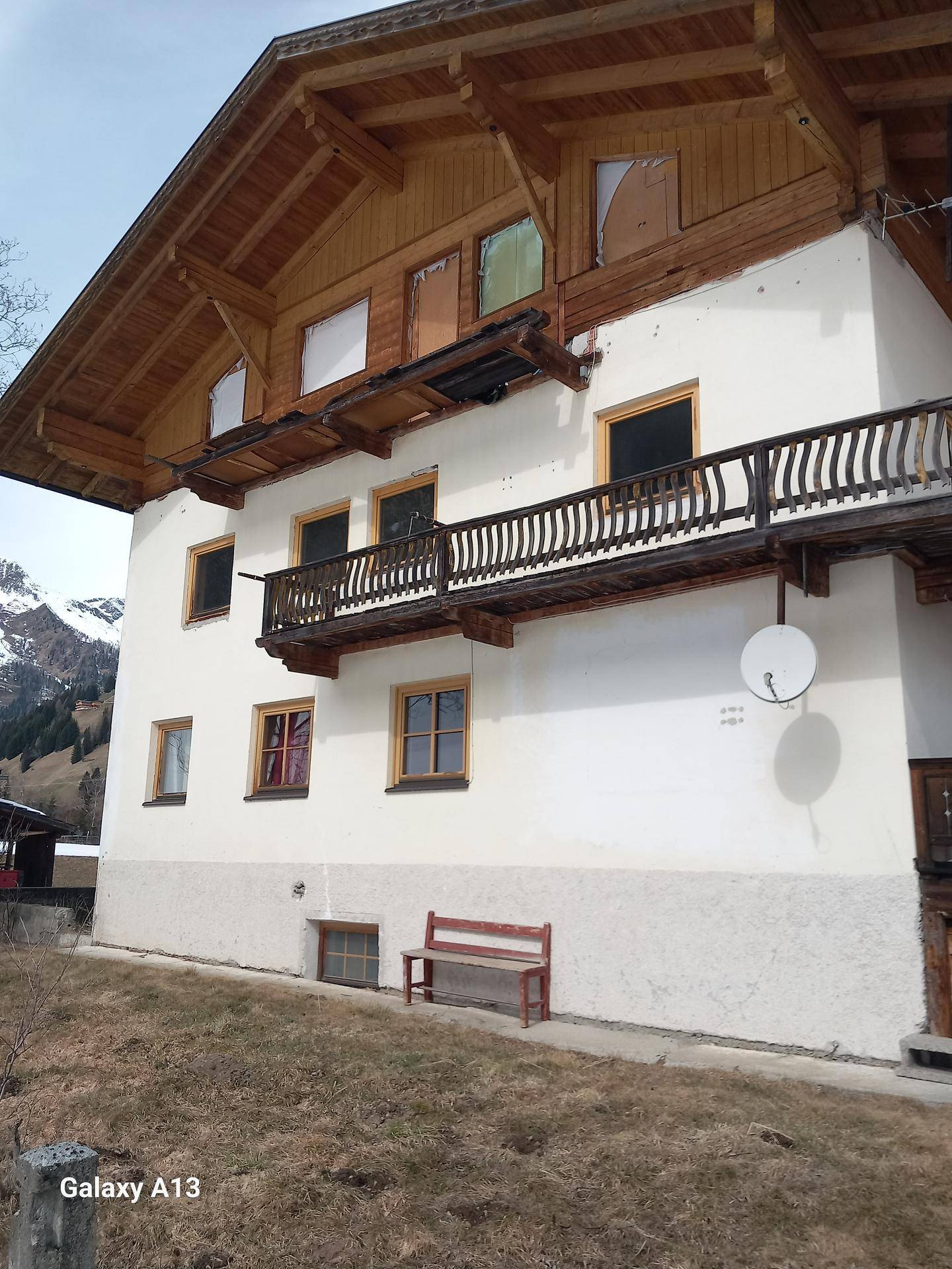 Fassade eines traditionellen Hauses mit Holzbalkonen und einem Satellitenempfänger an der Wand.
