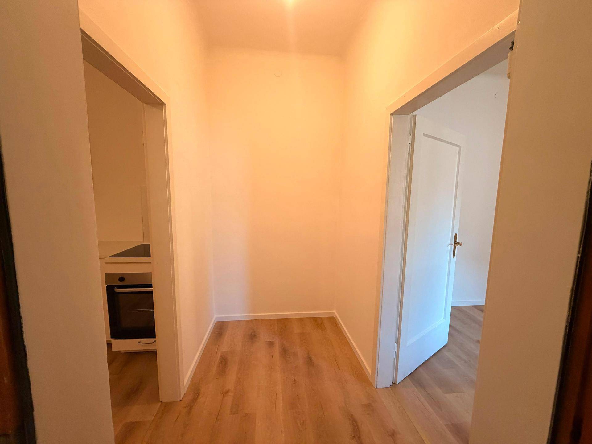 Heller Flur mit Laminatboden und Zugang zu angrenzenden Räumen, der eine praktische Verbindung schafft.