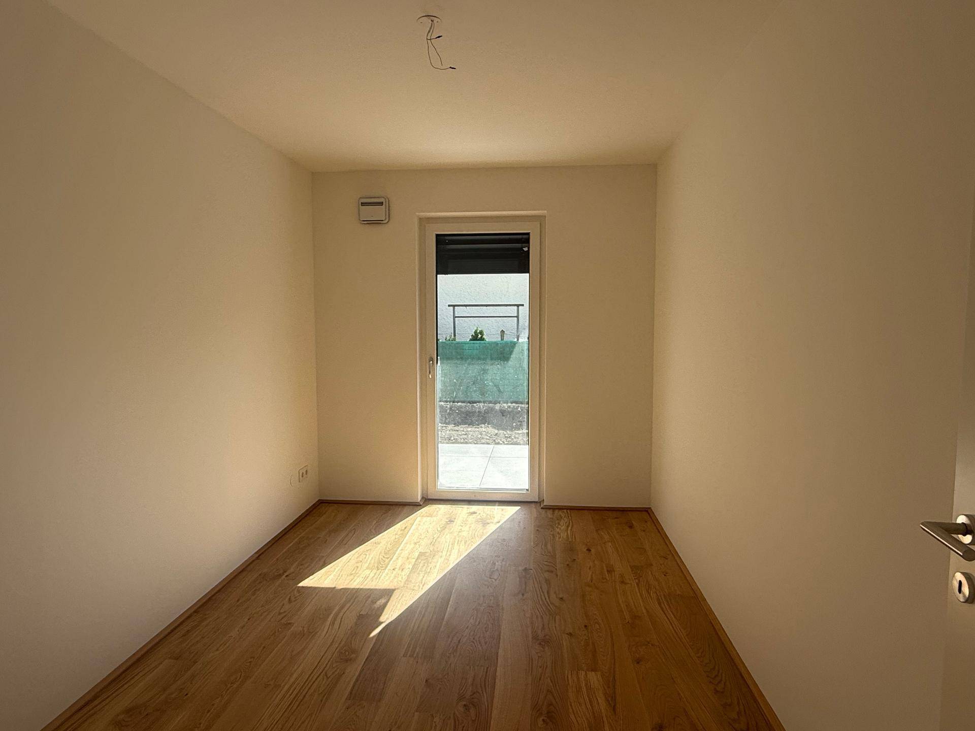 Gemütliches Schlafzimmer mit Holzboden und direktem Zugang zu einem Außenbereich.