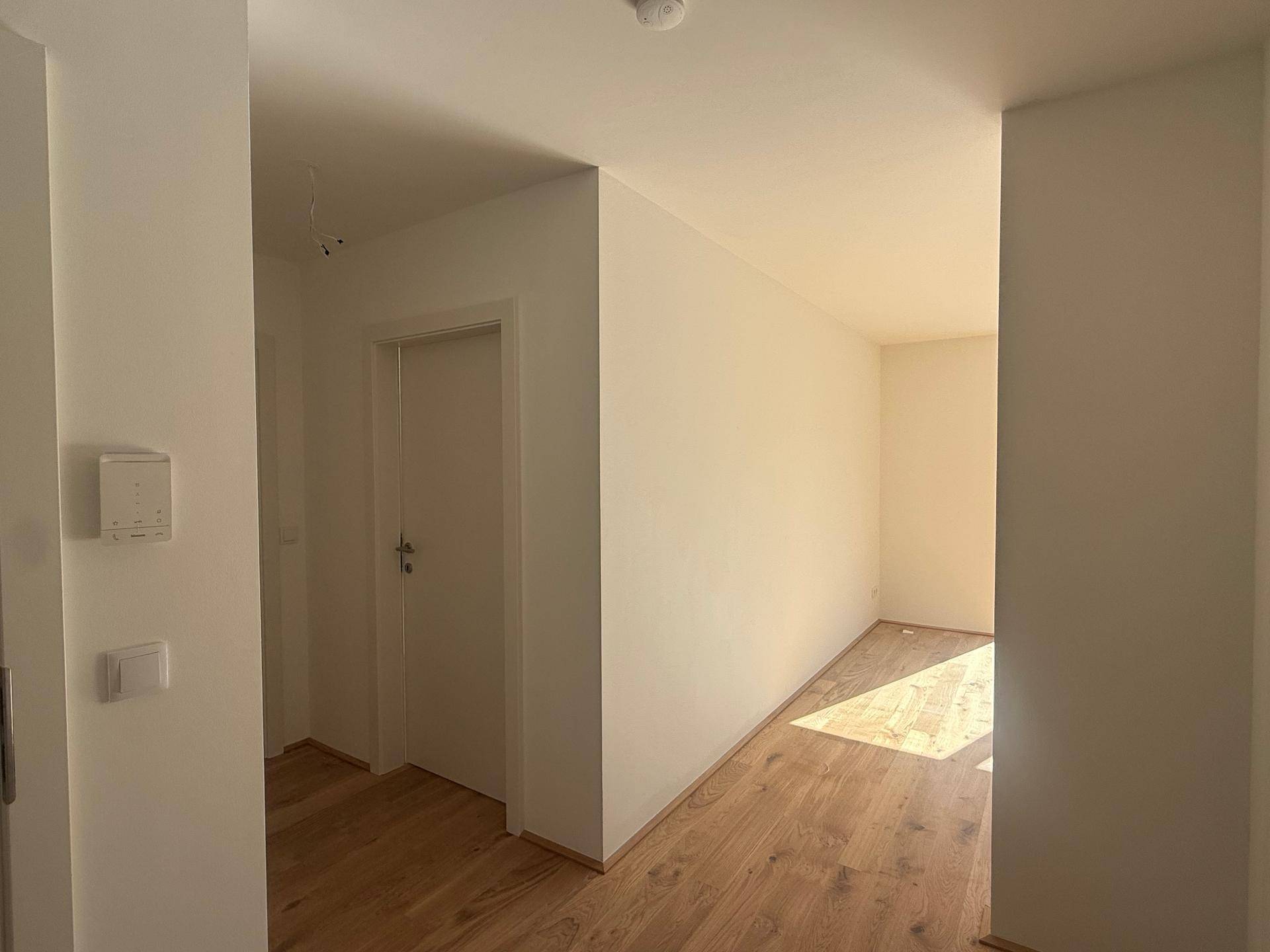 Heller Flur mit Parkettboden, der zu den verschiedenen Zimmern der Wohnung führt.