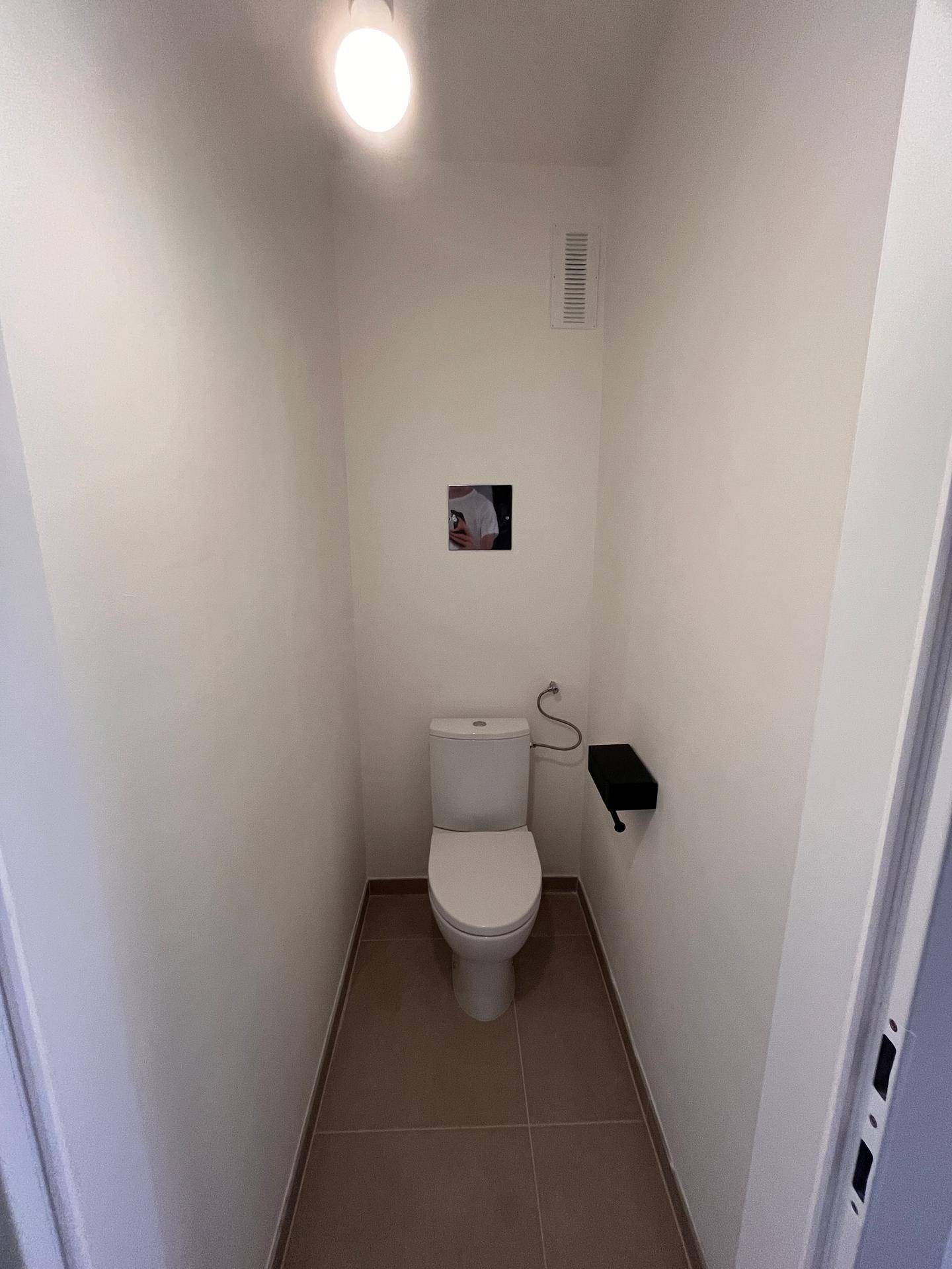 Kompaktes Gäste-WC mit weißer Toilette und hellen Fliesen, funktional und sauber gestaltet.