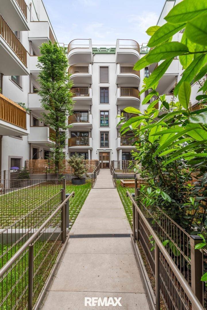 Moderner Innenhof einer Wohnanlage mit viel Grün, Gehwegen und Balkonen an den Fassaden.