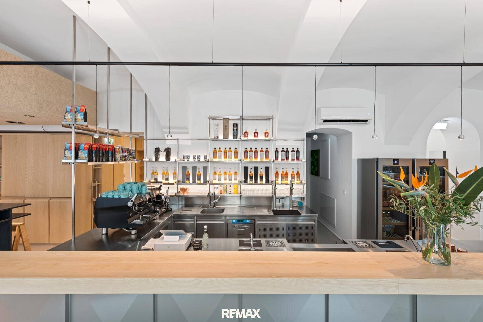 Moderne Bar mit Edelstahltheke, Holzarbeitsplatte und gewölbten Decken, ausgestattet mit professionellen Geräten.