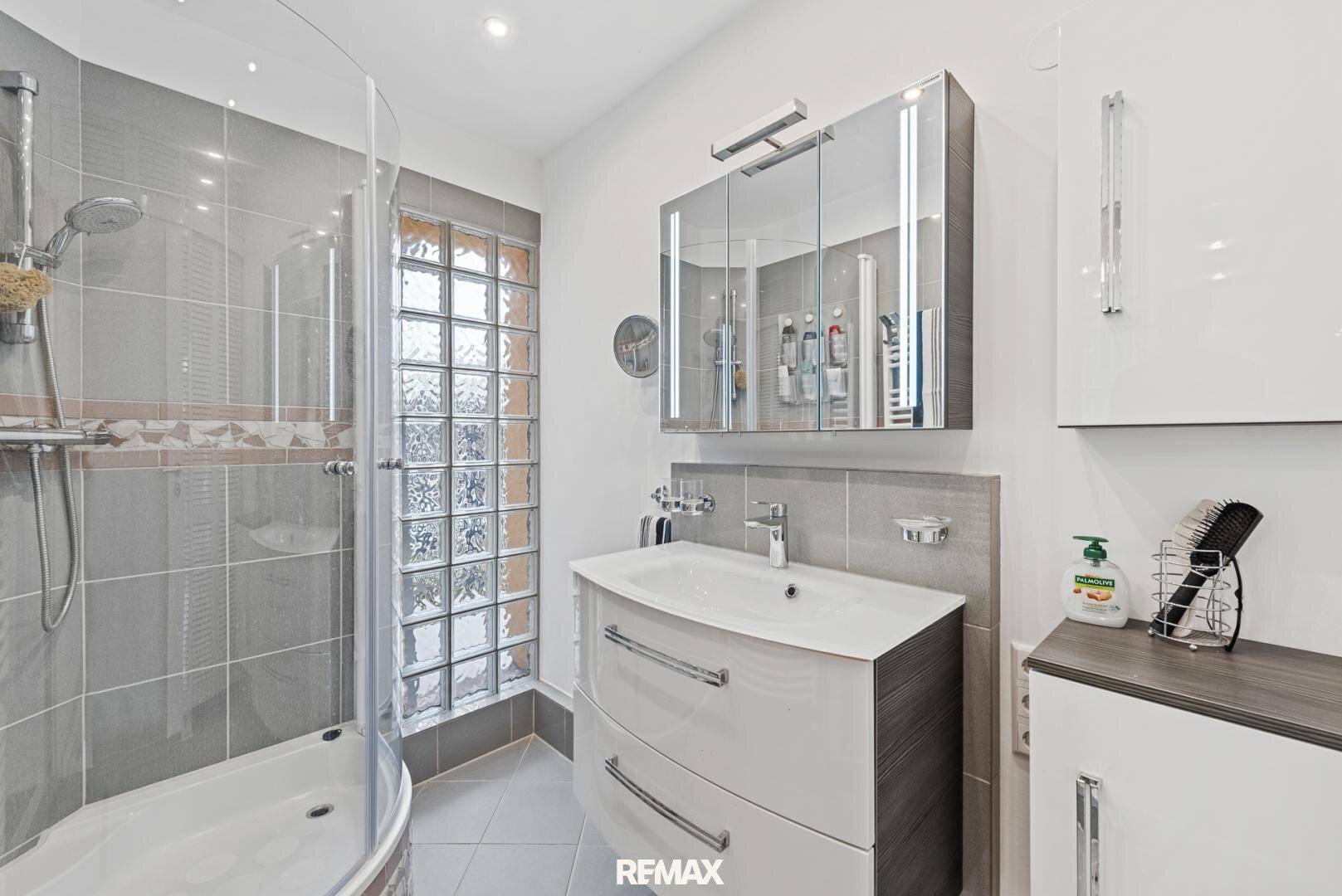 Modernes Badezimmer mit Duschkabine, Einzelwaschbecken und Spiegelschrank.