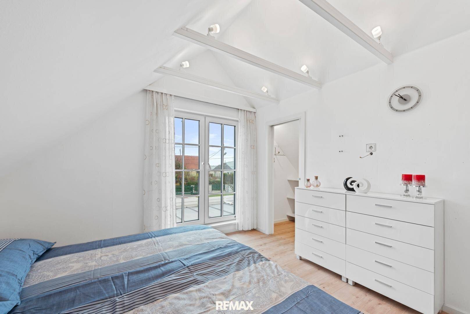 Helles Schlafzimmer im Dachgeschoss mit schrägen Wänden und Fenster.