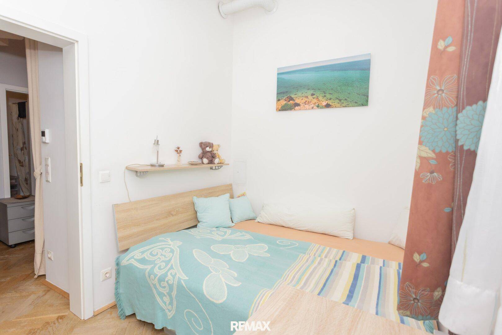 Helles Schlafzimmer mit Einzelbett, Holzfußboden und schlichter Einrichtung.