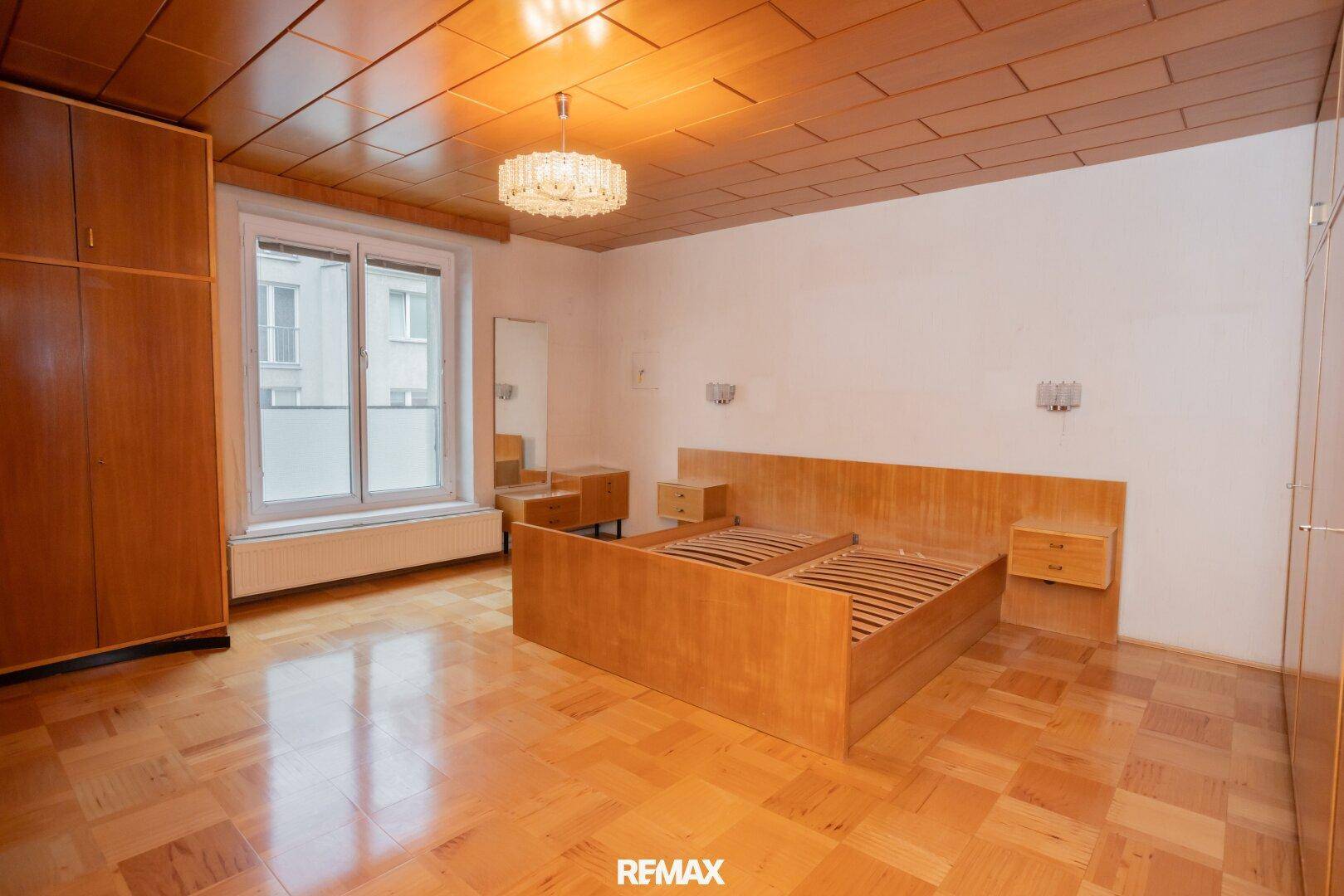 Schlafzimmer mit Holzparkett, einem Doppelbett und umfangreichen Einbauschränken, die viel Stauraum bieten.