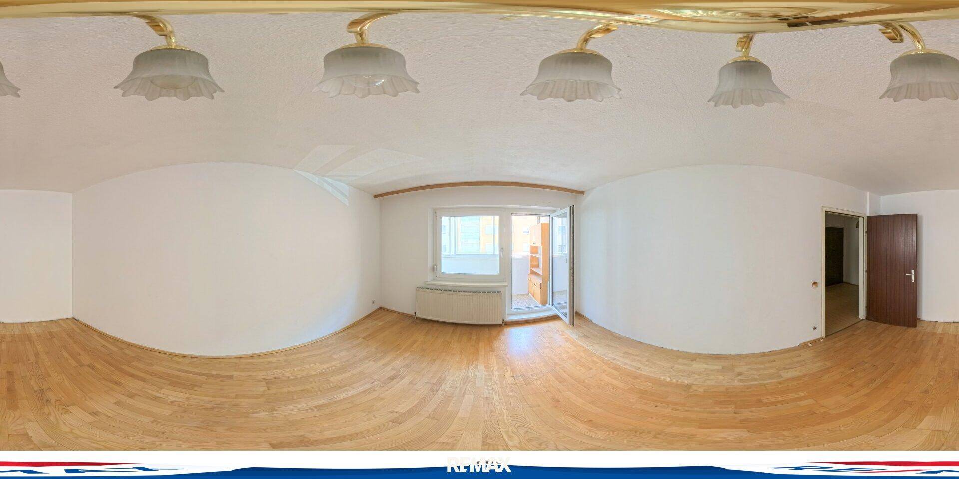 Heller, leerer Raum mit Holzboden, weißen Wänden und Zugang zu einem Außenbereich.