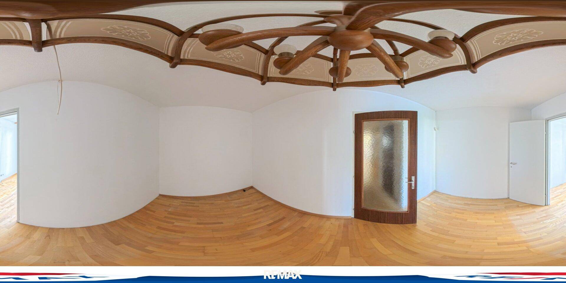 Leeres Schlafzimmer mit Holzboden, weißen Wänden und einem dekorativen Deckenventilator.