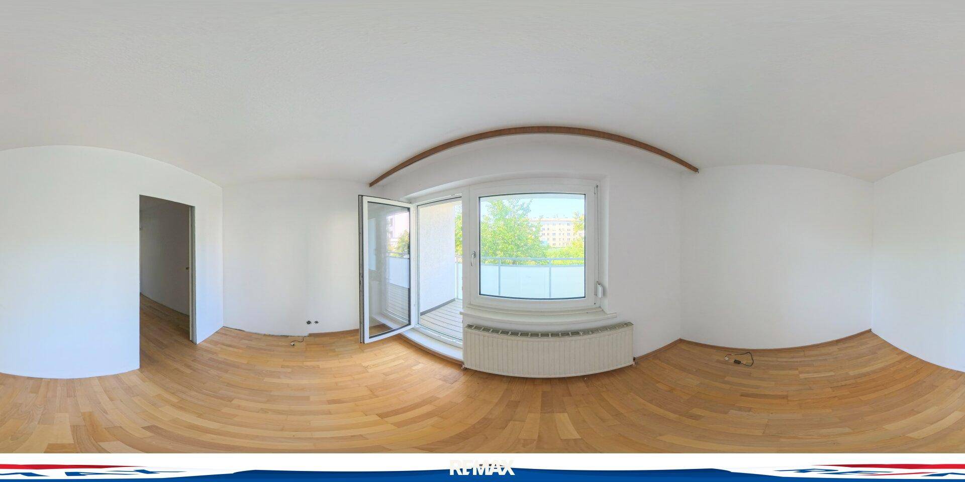 Heller, leerer Raum mit Holzboden, weißen Wänden und Zugang zu einem Außenbereich.