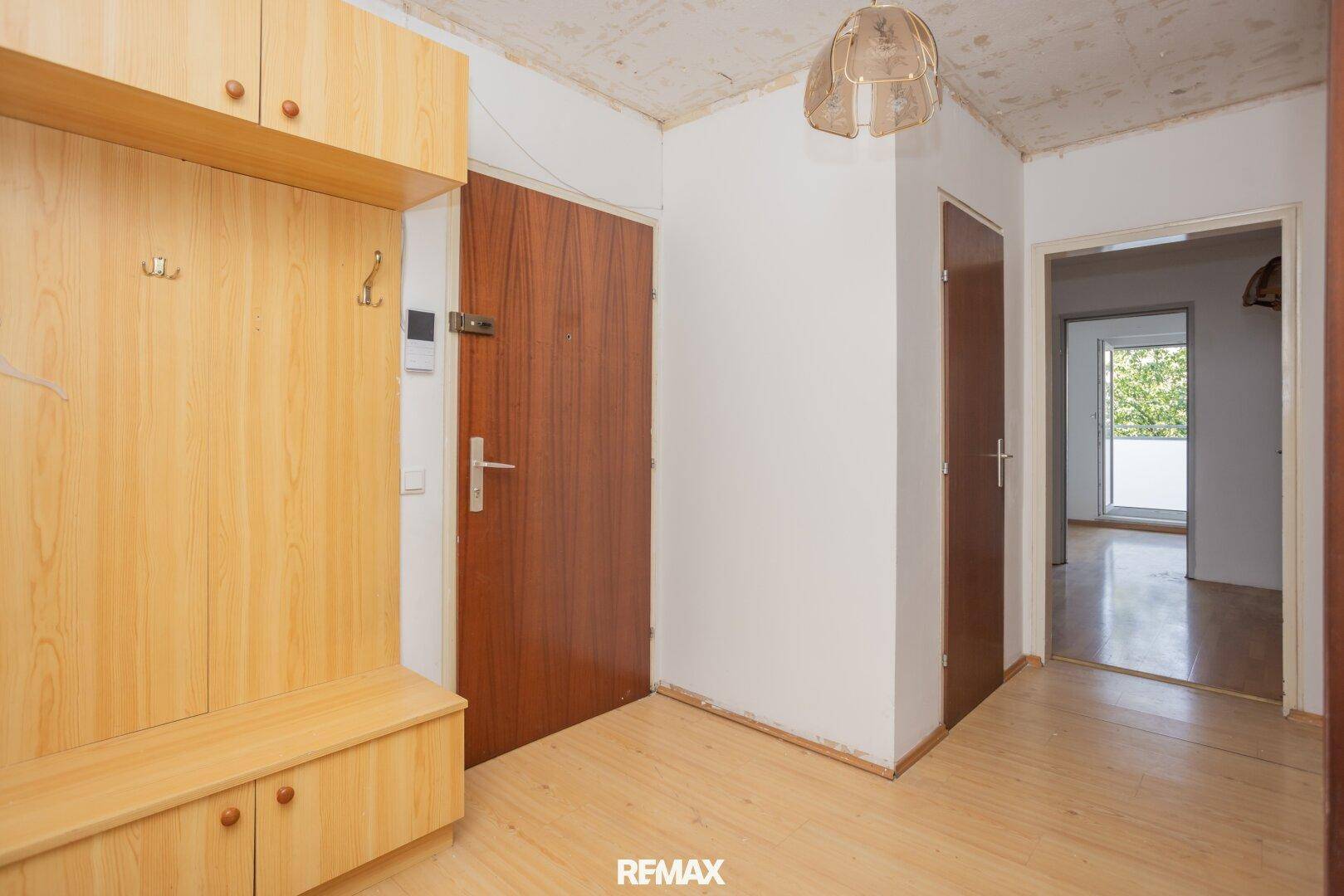 Eingangsbereich einer Wohnung mit Garderobe und Holztüren, in originalem Zustand.