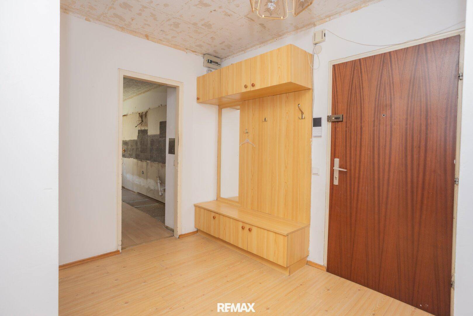 Flur mit alter Garderobe und Holzboden, der in weitere Räume der Wohnung führt.