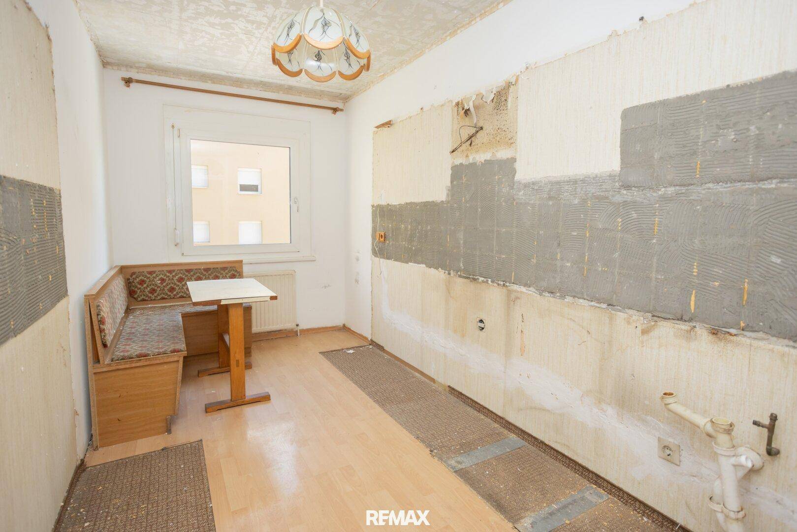 Leere Küche mit Fenster und Essbereich, bereit für eine neue Einrichtung und Renovierung.