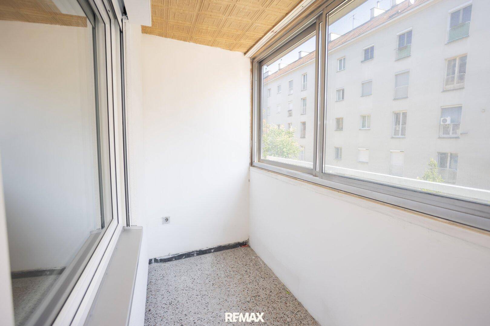 Verglaste Loggia mit Fliesenboden und Blick auf die Stadt, ideal als zusätzlicher Wohnraum.