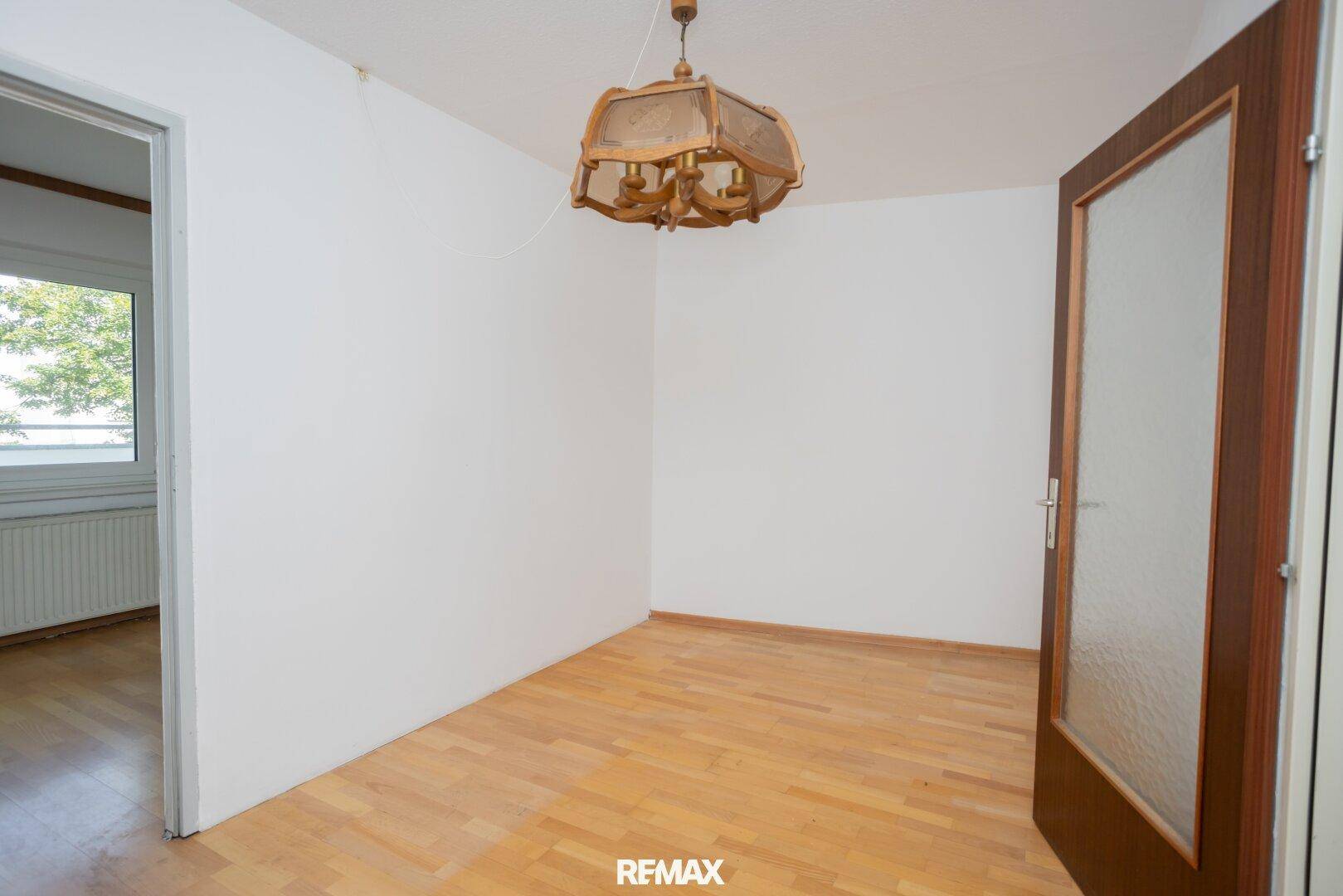Helles Zimmer mit Holzboden und Tür mit Glaseinsatz, unmöbliert und bereit zur Gestaltung.