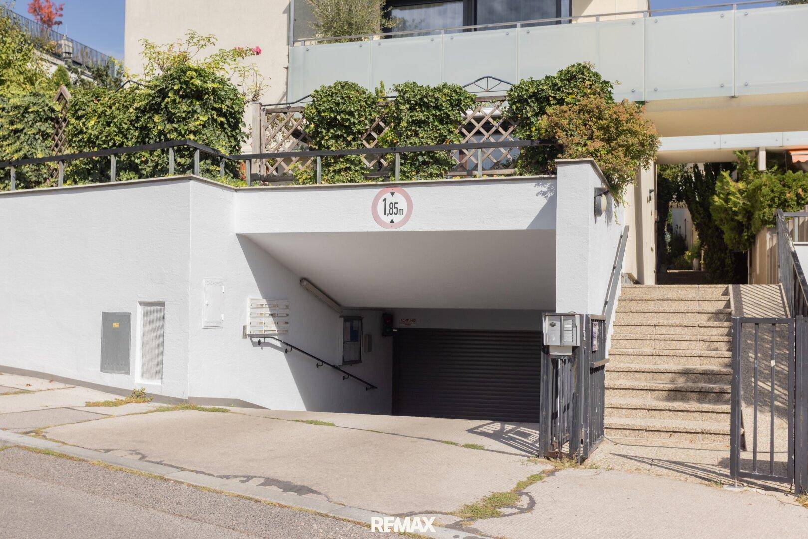 Tiefgaragenzufahrt mit Höhenbegrenzung und Treppenaufgang zu den Wohneinheiten.