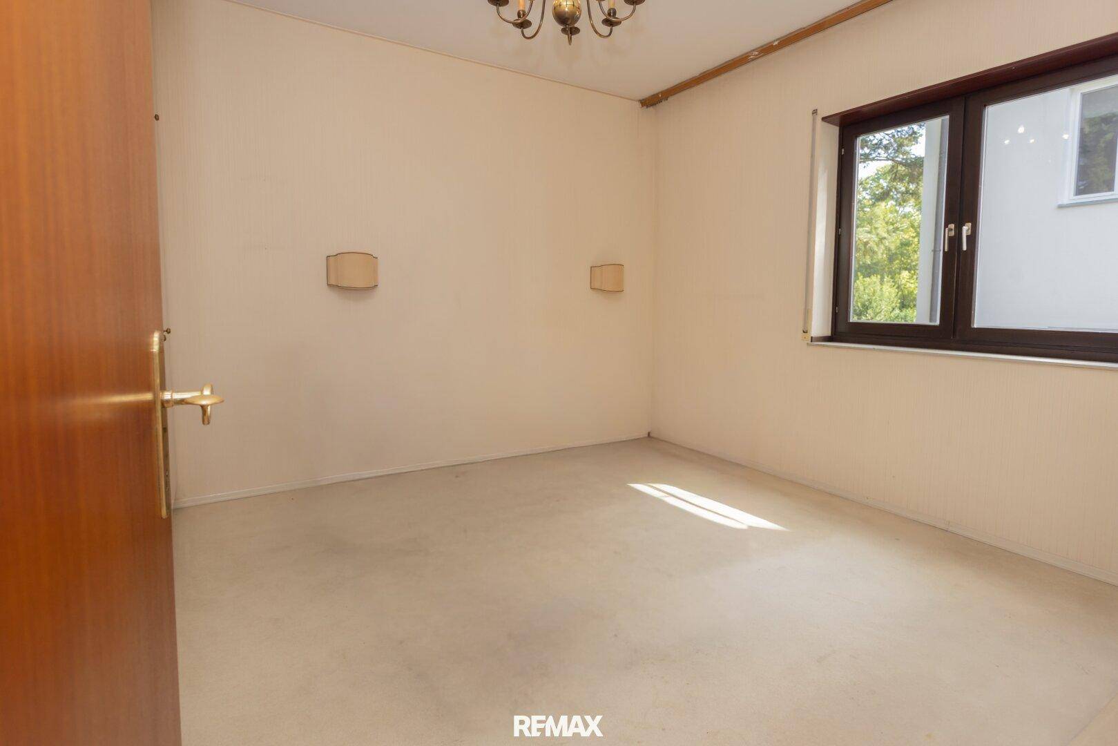 Helles Schlafzimmer mit Teppichboden und Fenster, das viel Tageslicht hereinlässt.