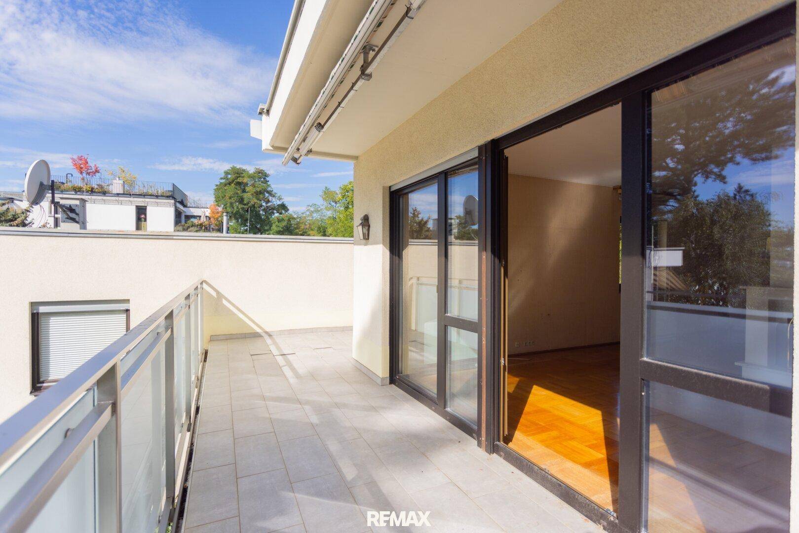 Geräumiger Balkon mit Fliesenboden und Glasgeländer, ideal für entspannte Stunden im Freien.