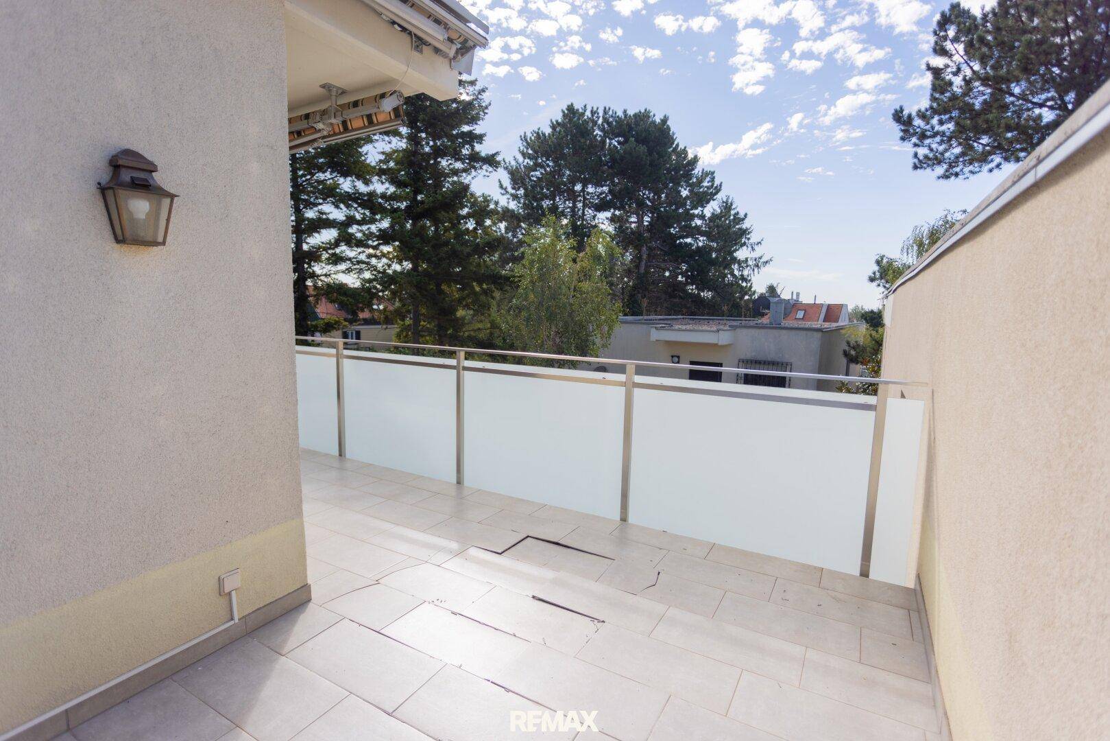 Heller Terrassenbereich mit moderner Glasbrüstung und weitem Blick in die Umgebung.