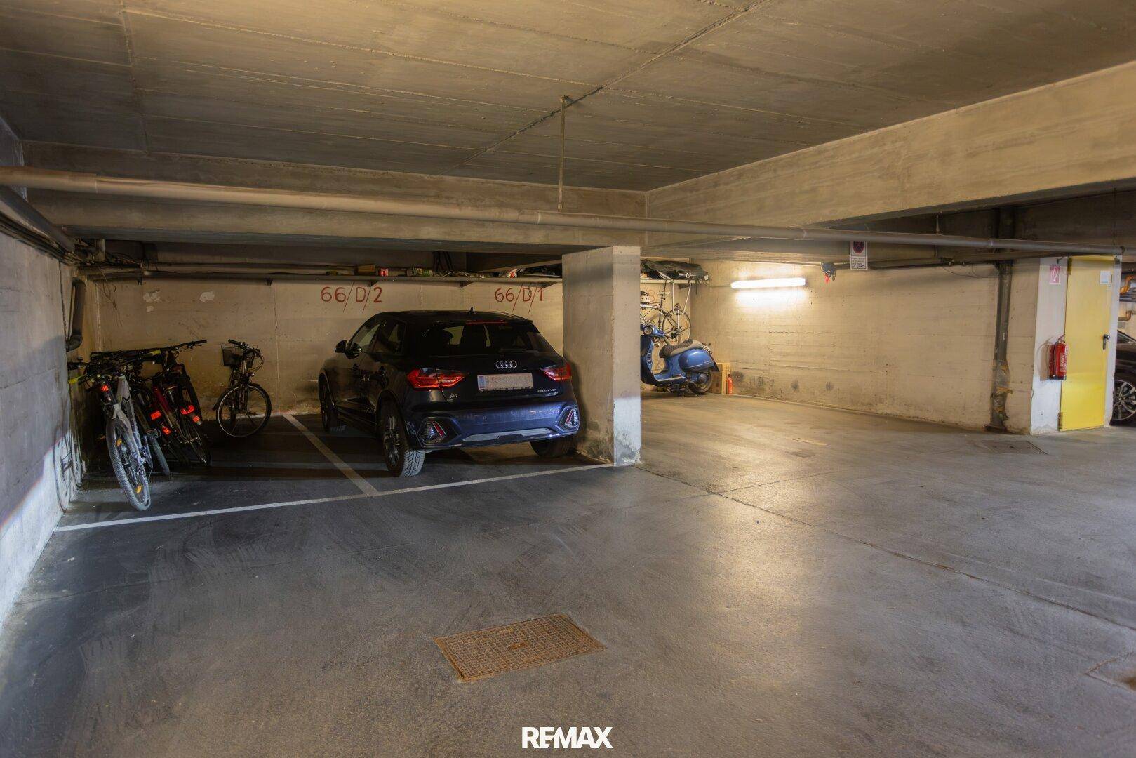 Geräumige Tiefgarage mit mehreren Stellplätzen, Fahrrädern und Motorroller.