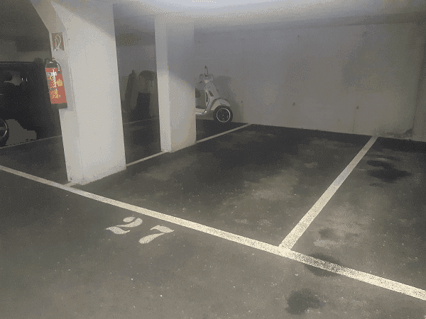 Geräumiger Tiefgaragenstellplatz Nummer 27 mit einem Roller im Hintergrund, gut zugänglich.