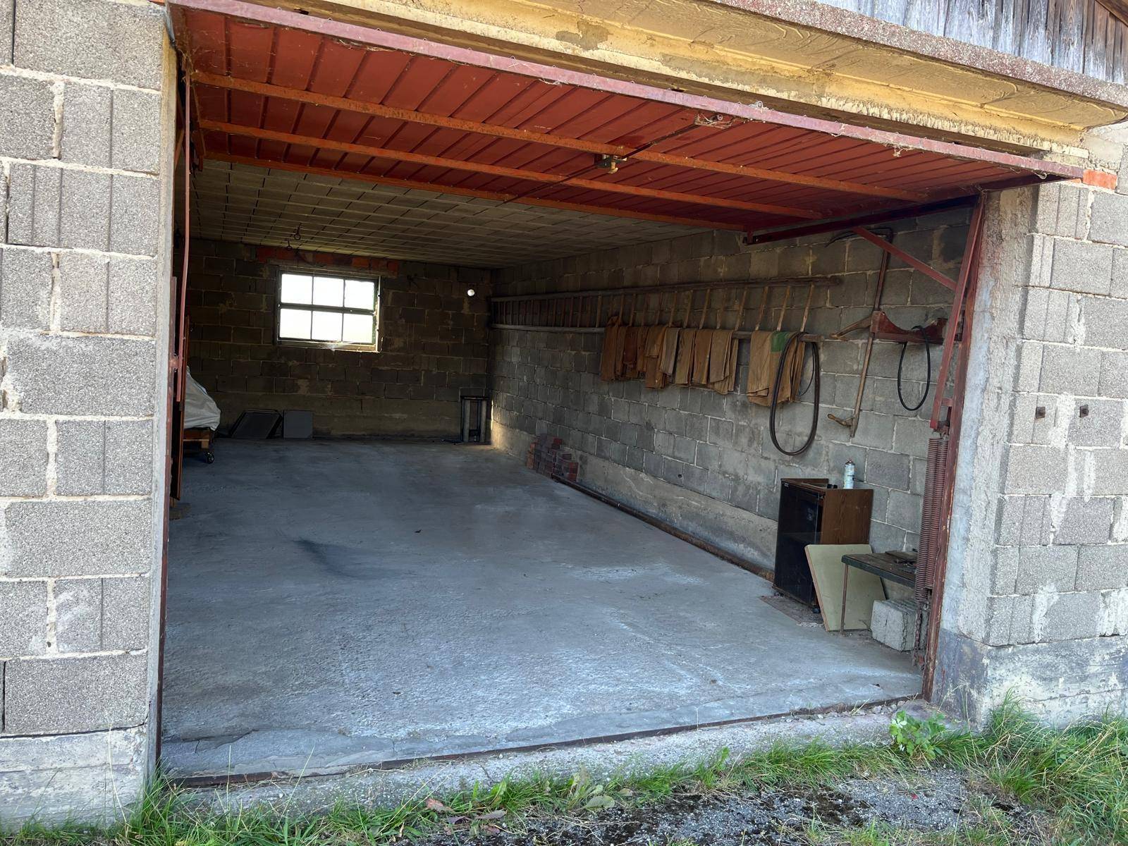 Blick in eine funktionale Garage mit unverputzten Betonwänden und einem strapazierfähigen Betonboden, gut beleuchtet.