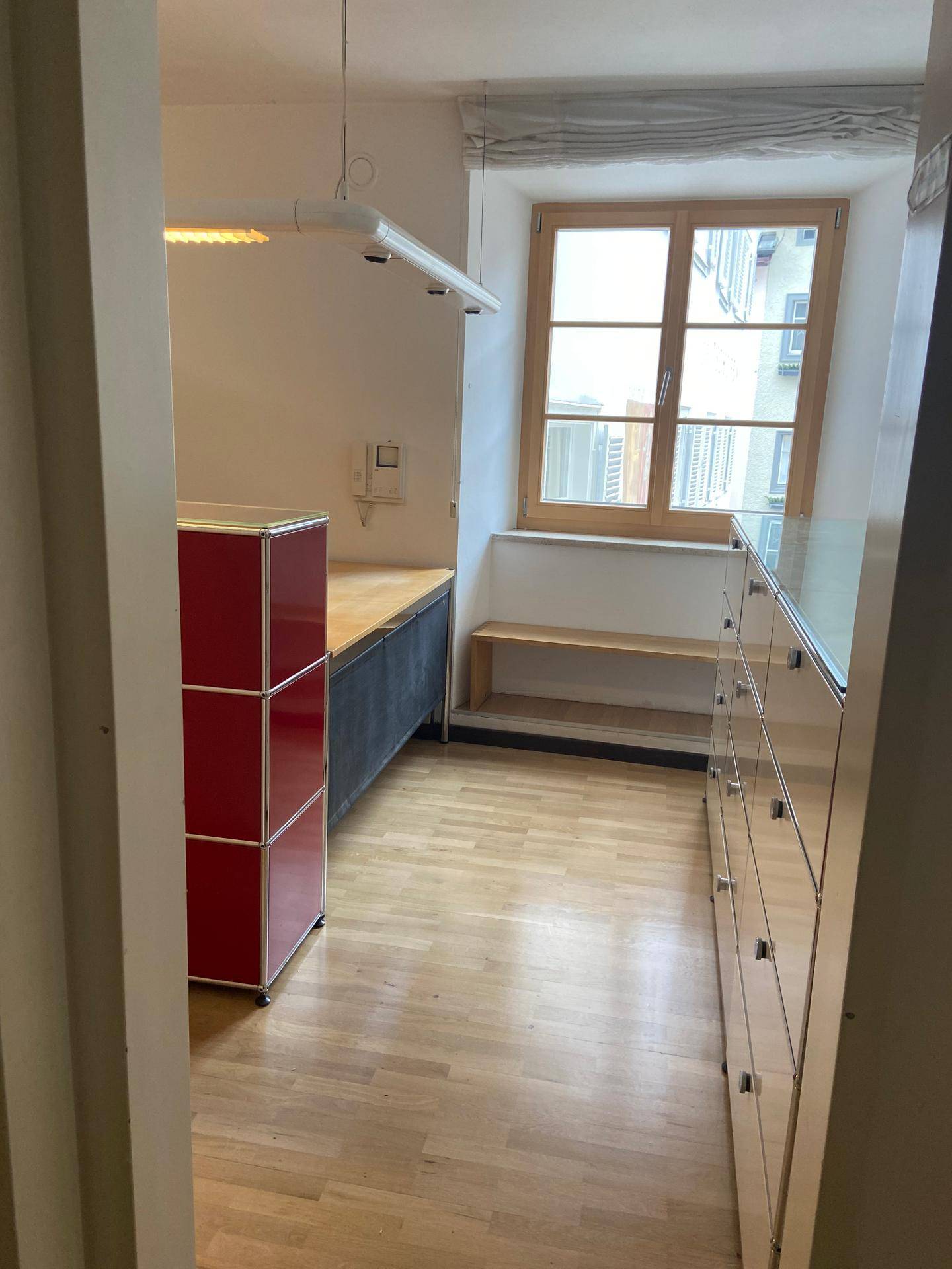 Heller Raum mit Holzfenster, Parkettboden und modernen modularen Möbeln in Rot und Weiß.