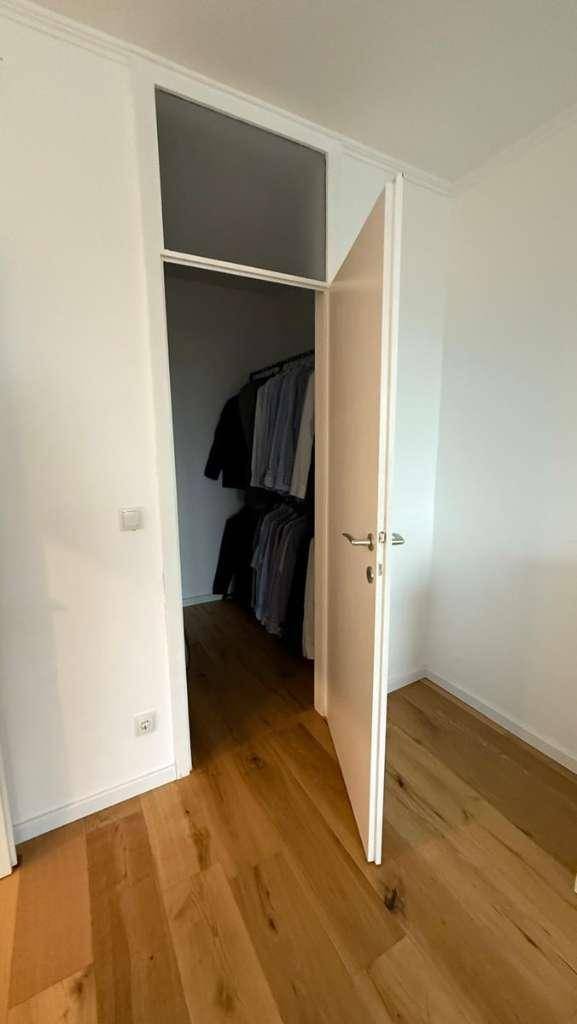 Schlafzimmer mit Holzboden und offenem Zugang zu einem begehbaren Kleiderschrank.