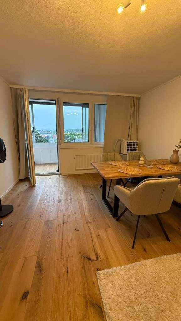 Essbereich mit Holztisch, Stühlen und Zugang zu einem Balkon mit Weitblick.
