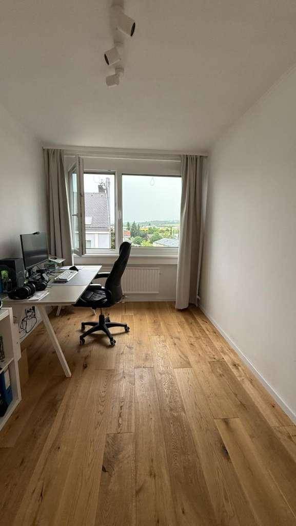 Helles Arbeitszimmer mit Holzboden, Schreibtisch und Fenster mit Weitblick ins Grüne.