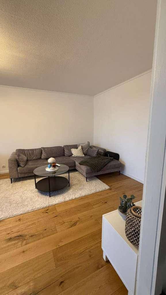 Gemütliches Wohnzimmer mit großem Ecksofa, Couchtisch und hellem Holzboden.