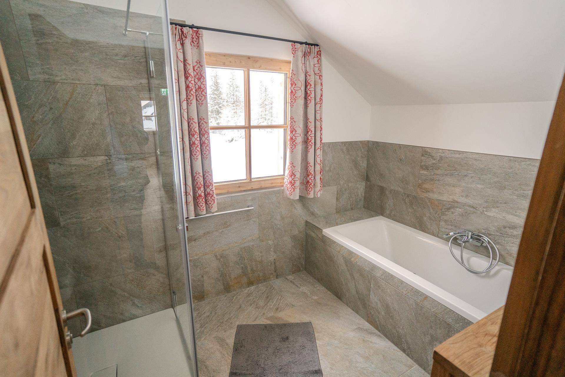 Geräumiges Badezimmer mit Badewanne, Glasdusche und Fenster, bietet Komfort und Helligkeit.