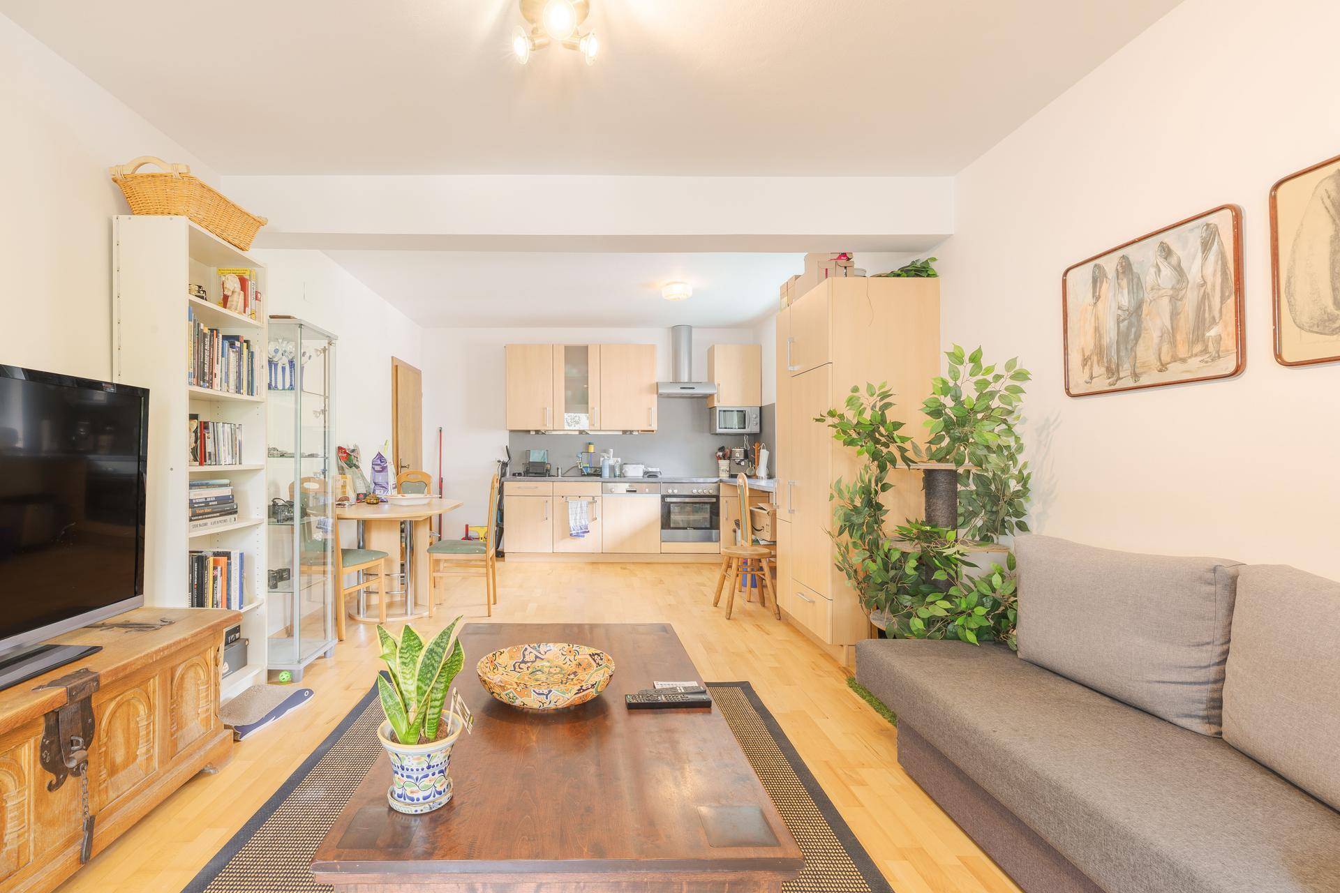 Heller Wohn-Essbereich mit Holzboden, bequemer Couch und offener Küche im Hintergrund.
