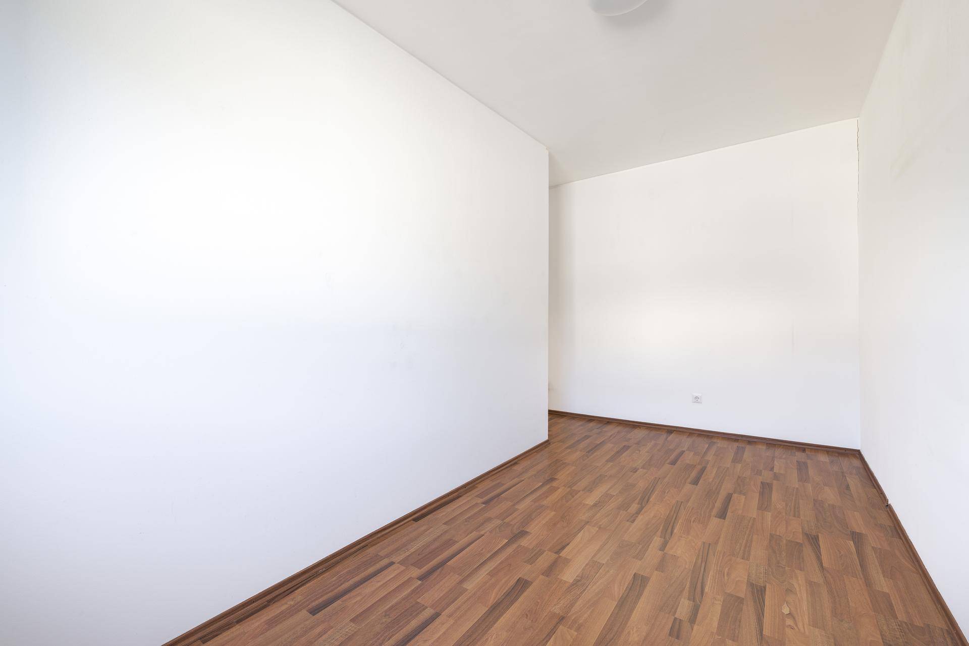 Unmöbliertes Zimmer mit Laminatboden und weißen Wänden, bereit zur individuellen Gestaltung.