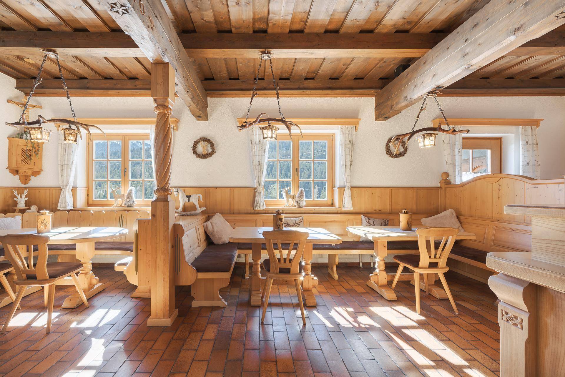 Heller Essbereich mit Holzbalkendecke, großen Fenstern und traditionellen Holzmöbeln.