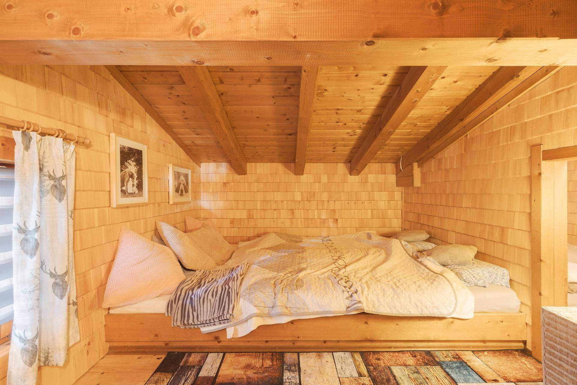 Kleines, gemütliches Schlafzimmer mit eingebautem Holzbett, Wänden aus Holzschindeln und sichtbaren Deckenbalken.