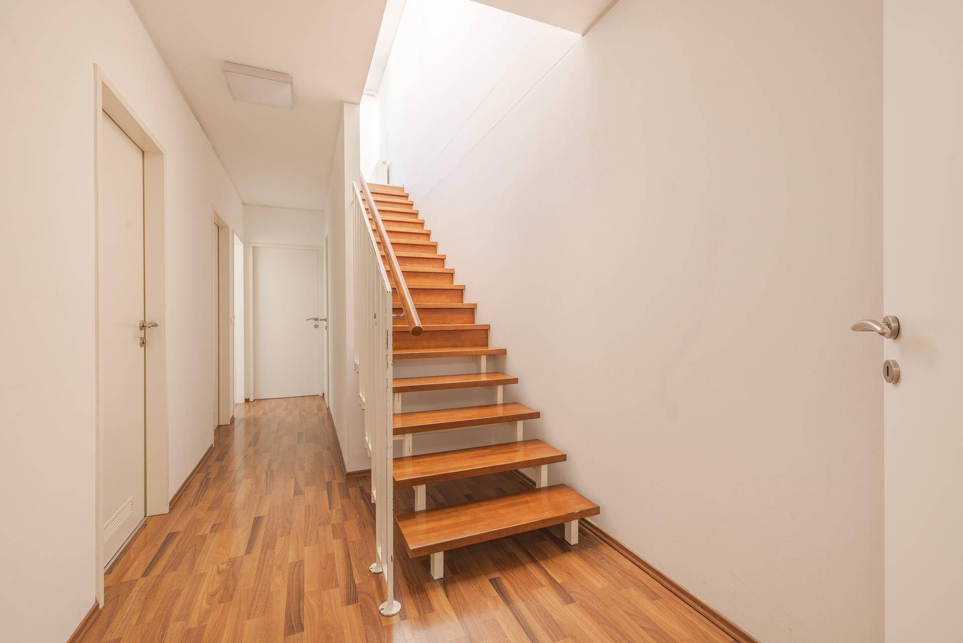 Heller Flur mit Holztreppe und Laminatboden, der die verschiedenen Ebenen der Maisonette verbindet.