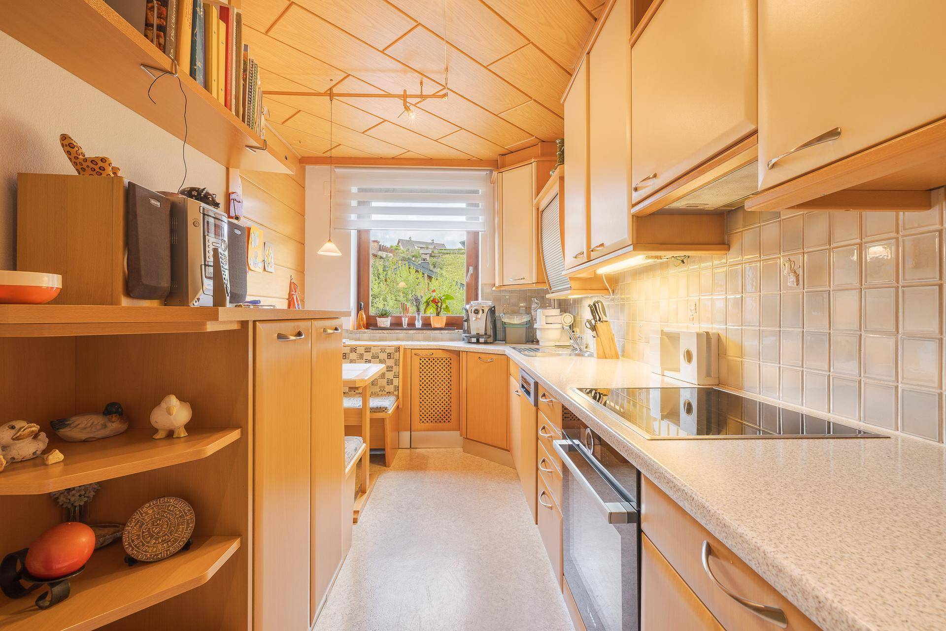 Funktionale Küche im Landhausstil mit Holzelementen, Einbaugeräten und Blick auf die Landschaft.