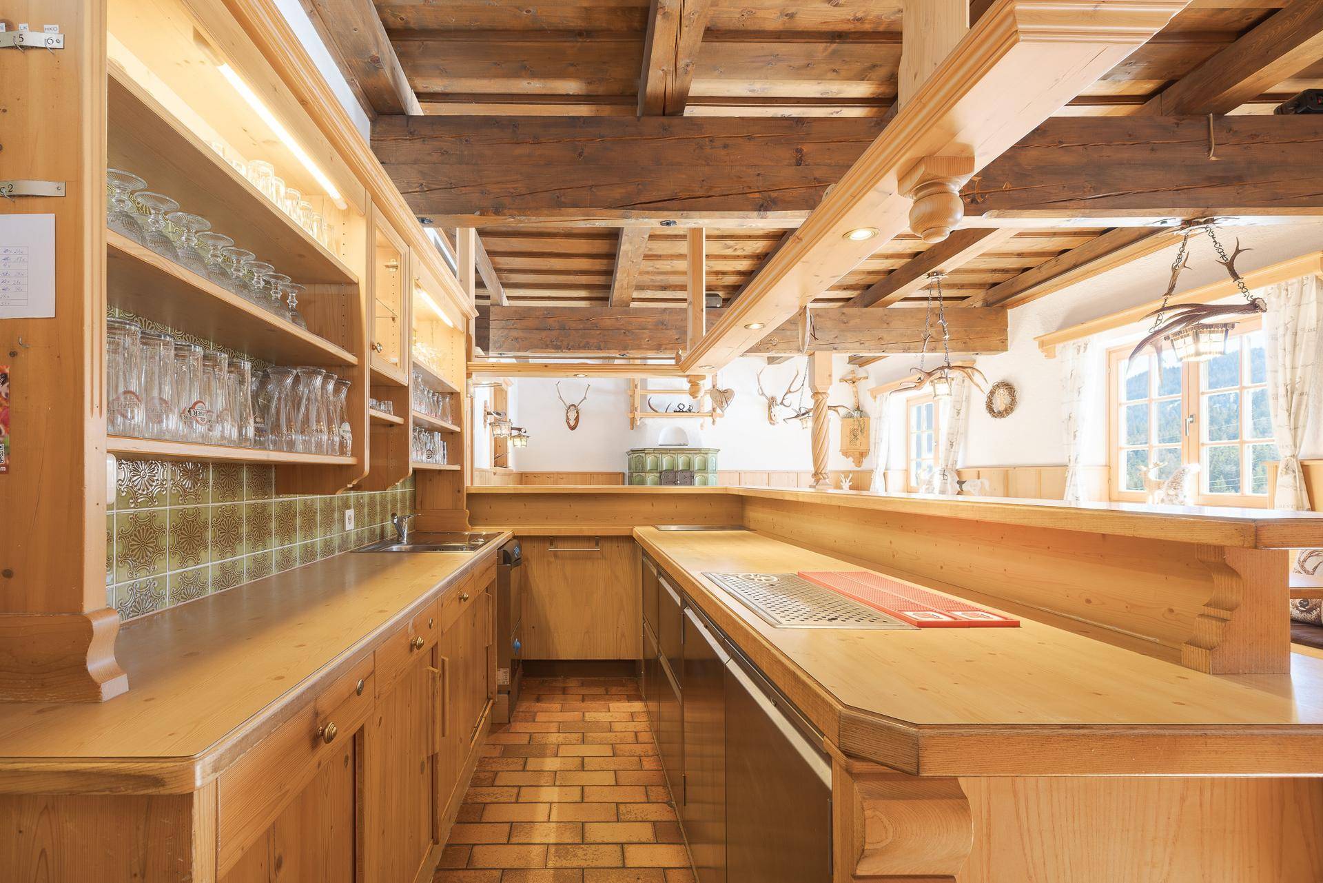 Traditionelle Holzküche mit Theke, Fliesenboden und integrierten Regalen für Gläser.