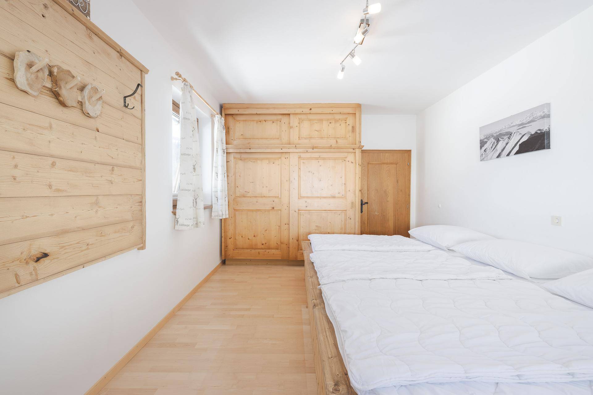 Schlafzimmer mit Doppelbett, Einbauschrank aus Holz und hellem Laminatboden.