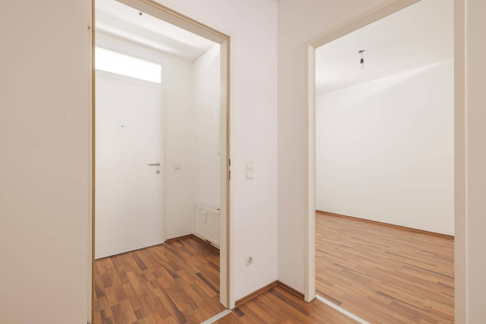 Flur mit Laminatboden und weißen Türen, der zu verschiedenen Räumen der Wohnung führt.