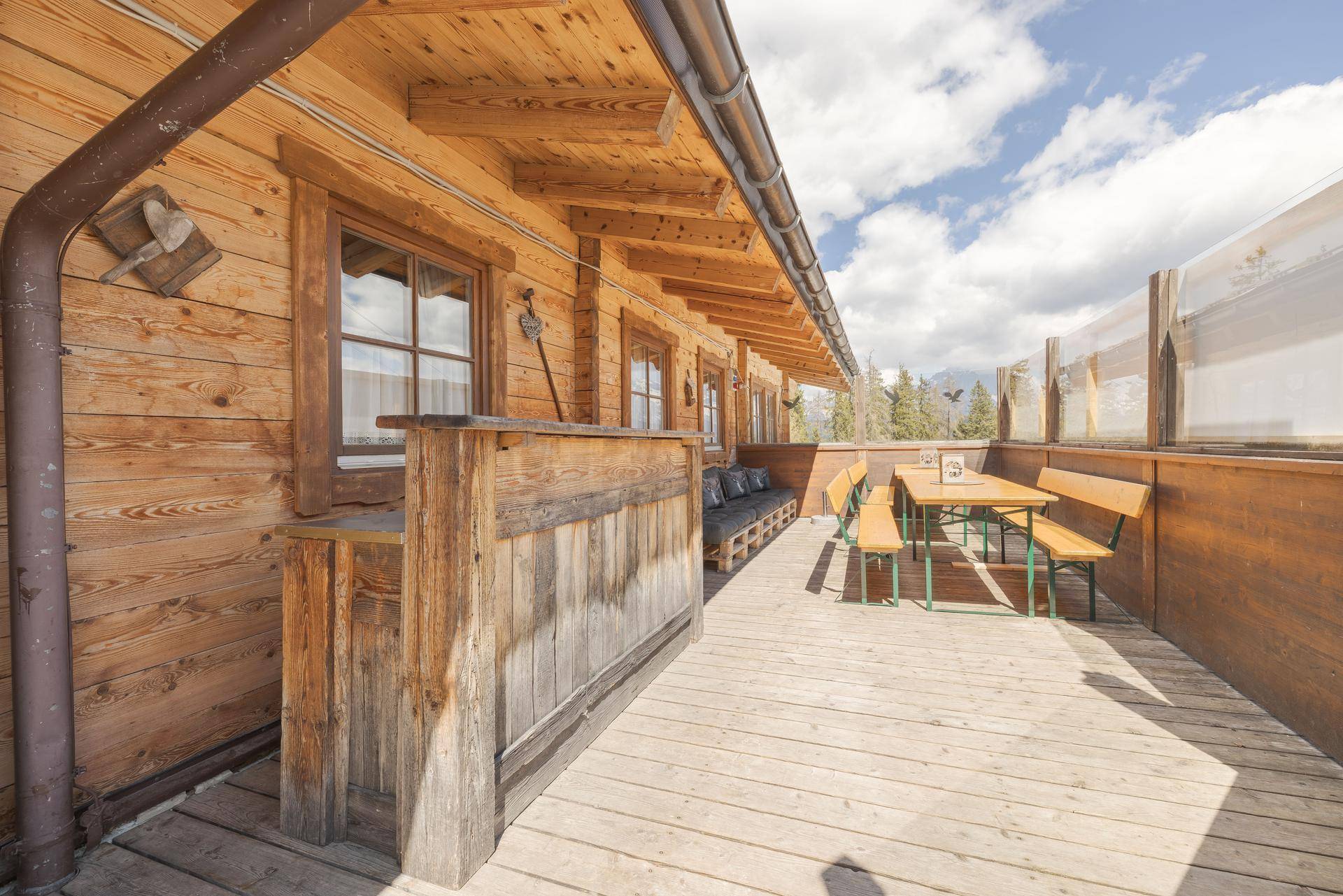 Geräumige Holzterrasse mit rustikalen Sitzgelegenheiten und weitem Blick auf die umliegende Berglandschaft.