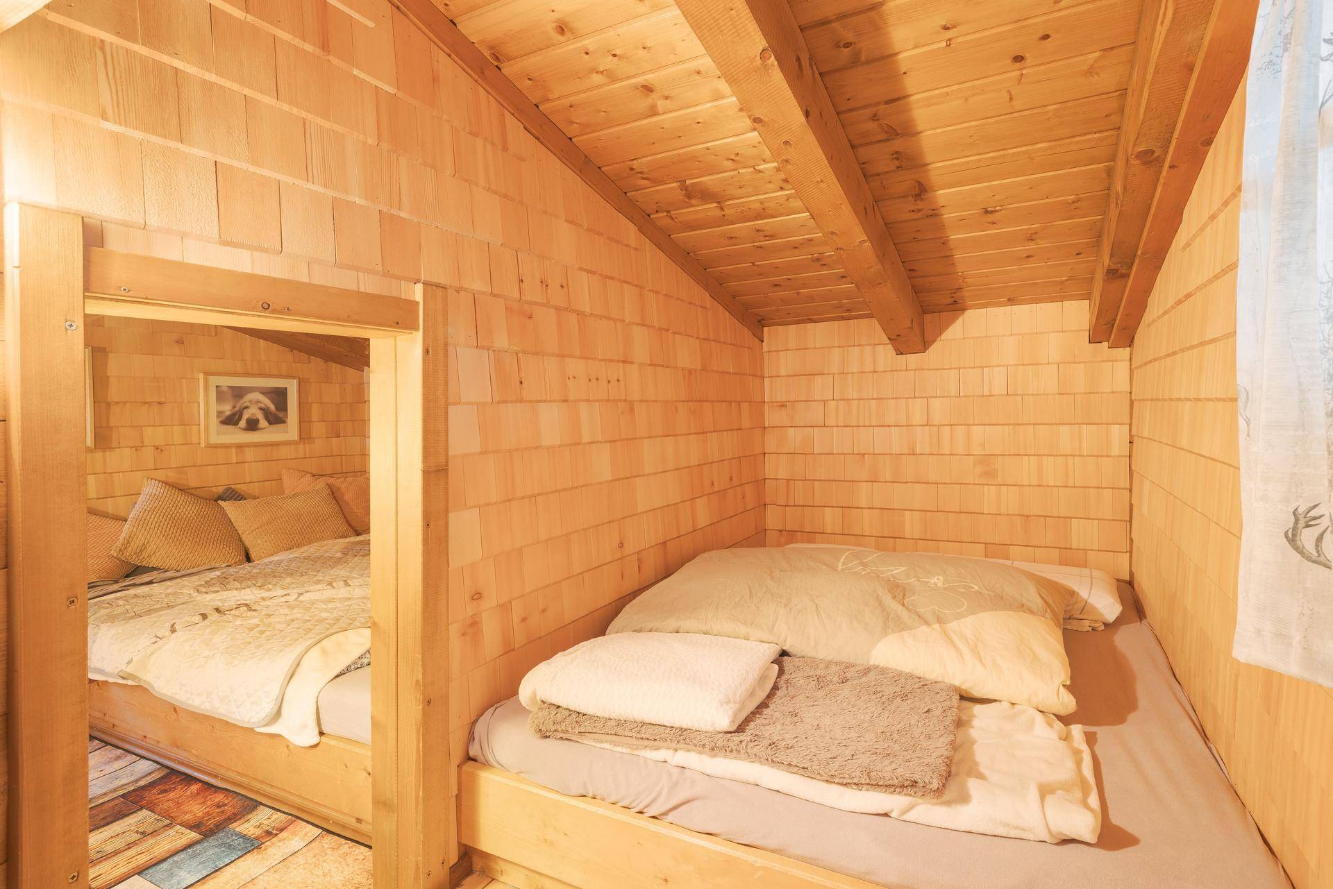 Schlafzimmer mit zwei eingebauten Holzbetten, Wänden aus Holzschindeln und rustikalem Holzdecken-Design.
