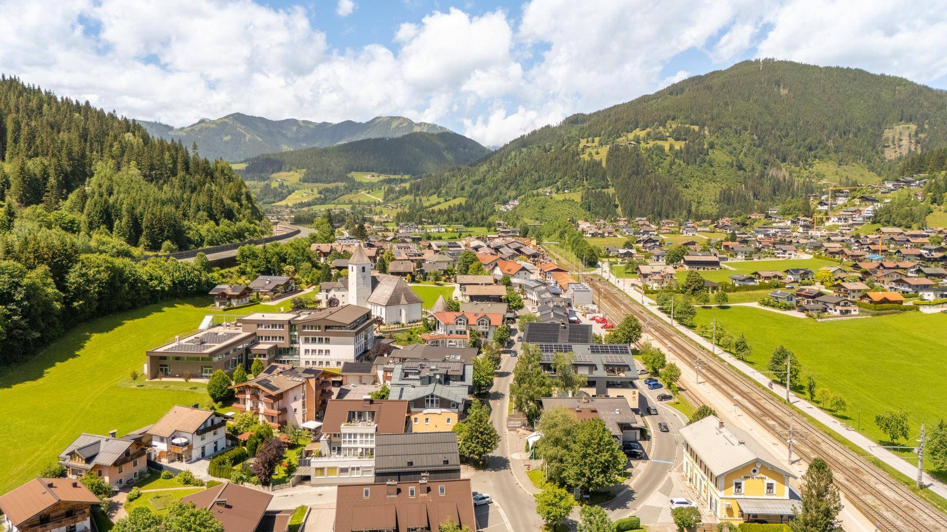 Malerische Luftaufnahme eines Dorfes in den Bergen mit grünen Wiesen und Häusern.