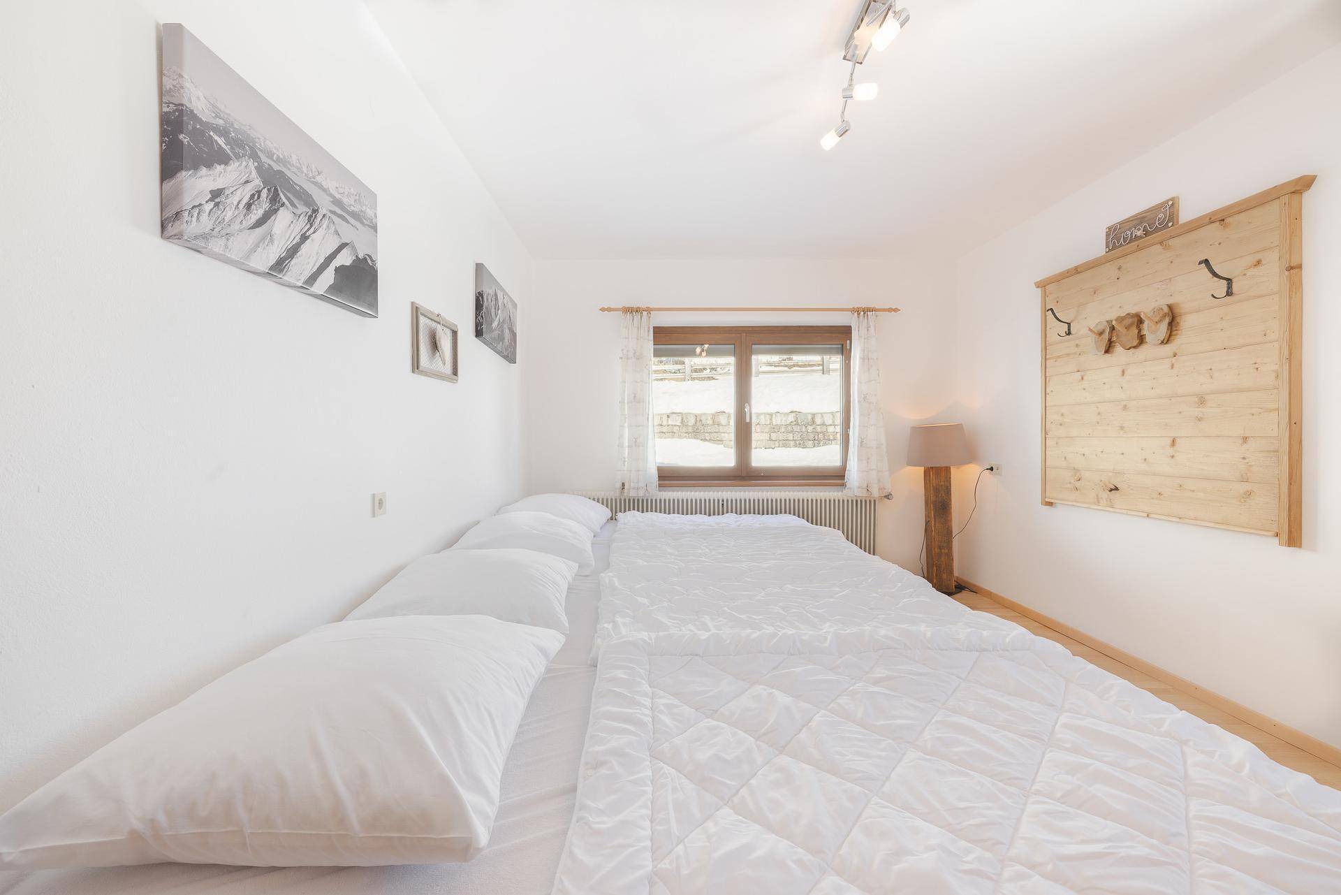 Helles Schlafzimmer mit Doppelbett, weißen Wänden und Blick auf die verschneite Landschaft.