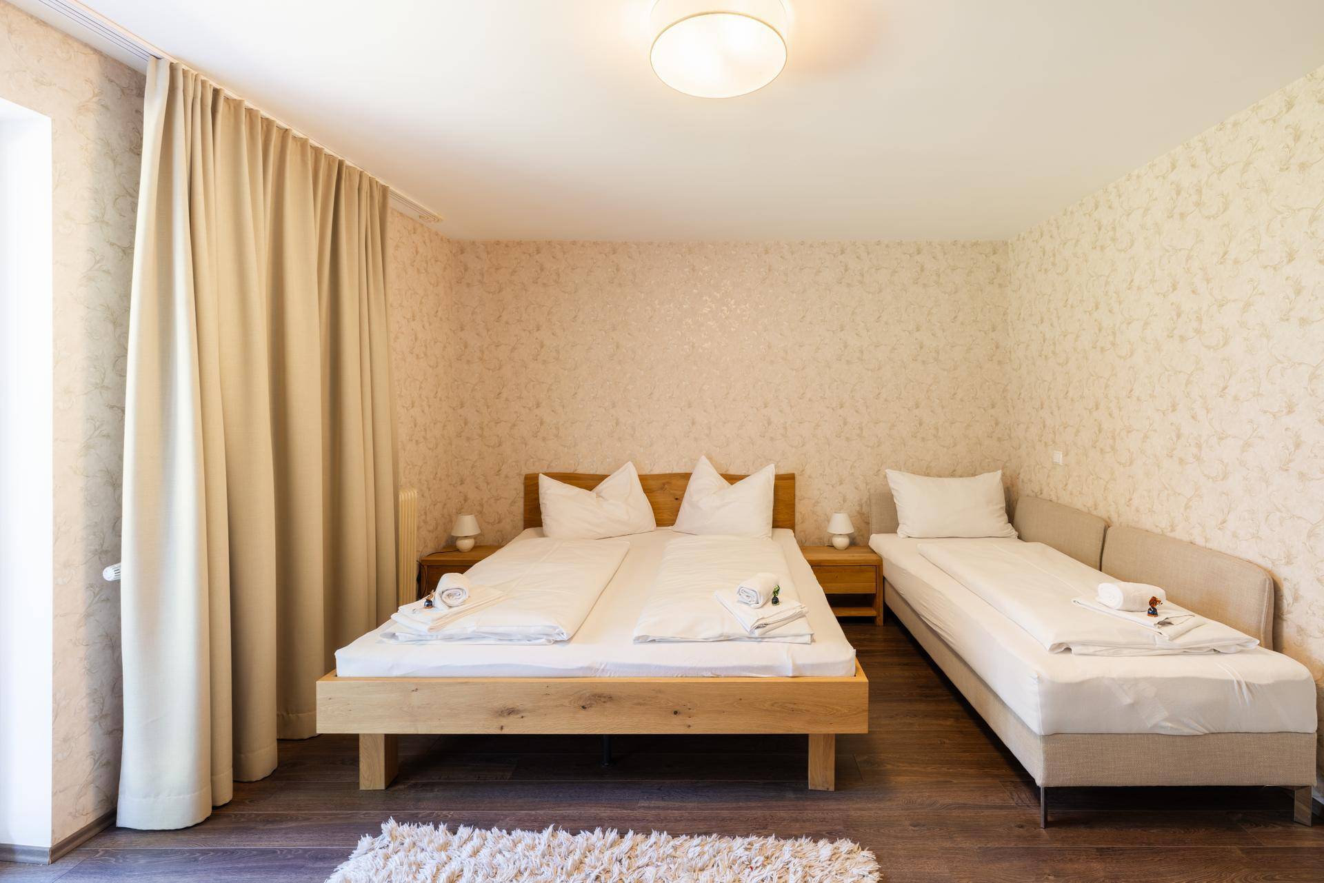 Gemütliches Schlafzimmer mit Doppelbett und Einzelbett, Holzboden und heller Einrichtung.