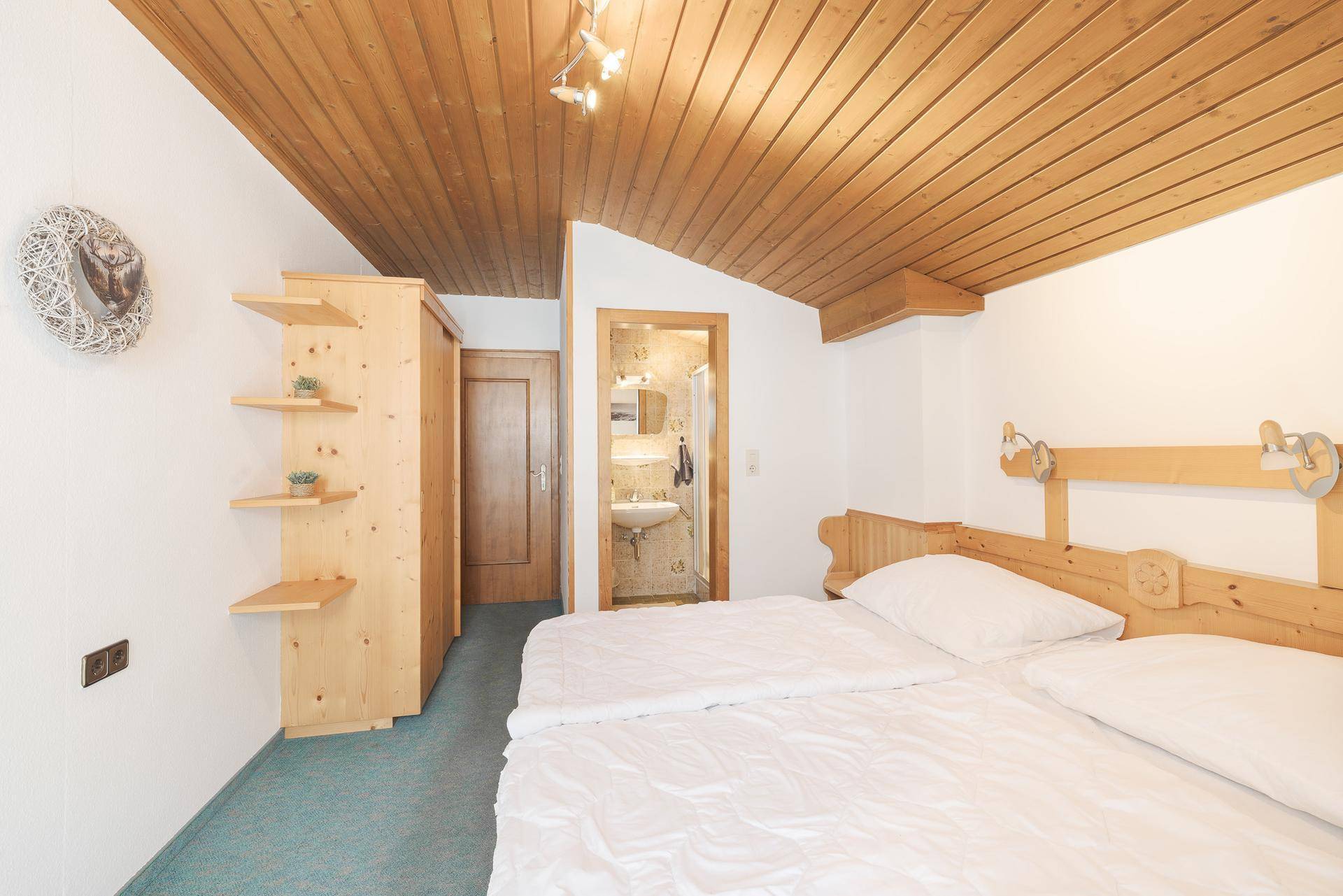 Schlafzimmer mit Doppelbett, Holzdecke und angrenzendem Badezimmer.