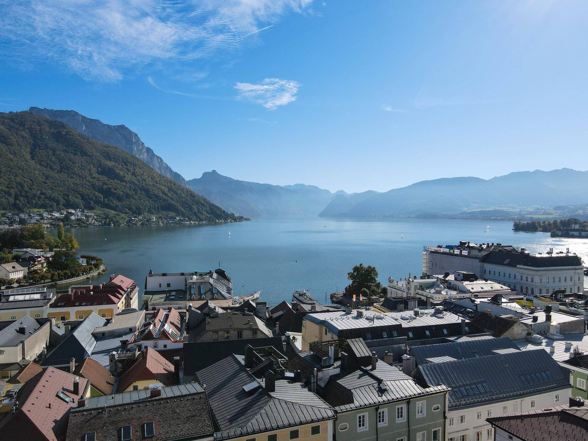 Atemberaubender Ausblick über die Stadt auf den glitzernden See und die majestätischen Berge unter blauem Himmel.