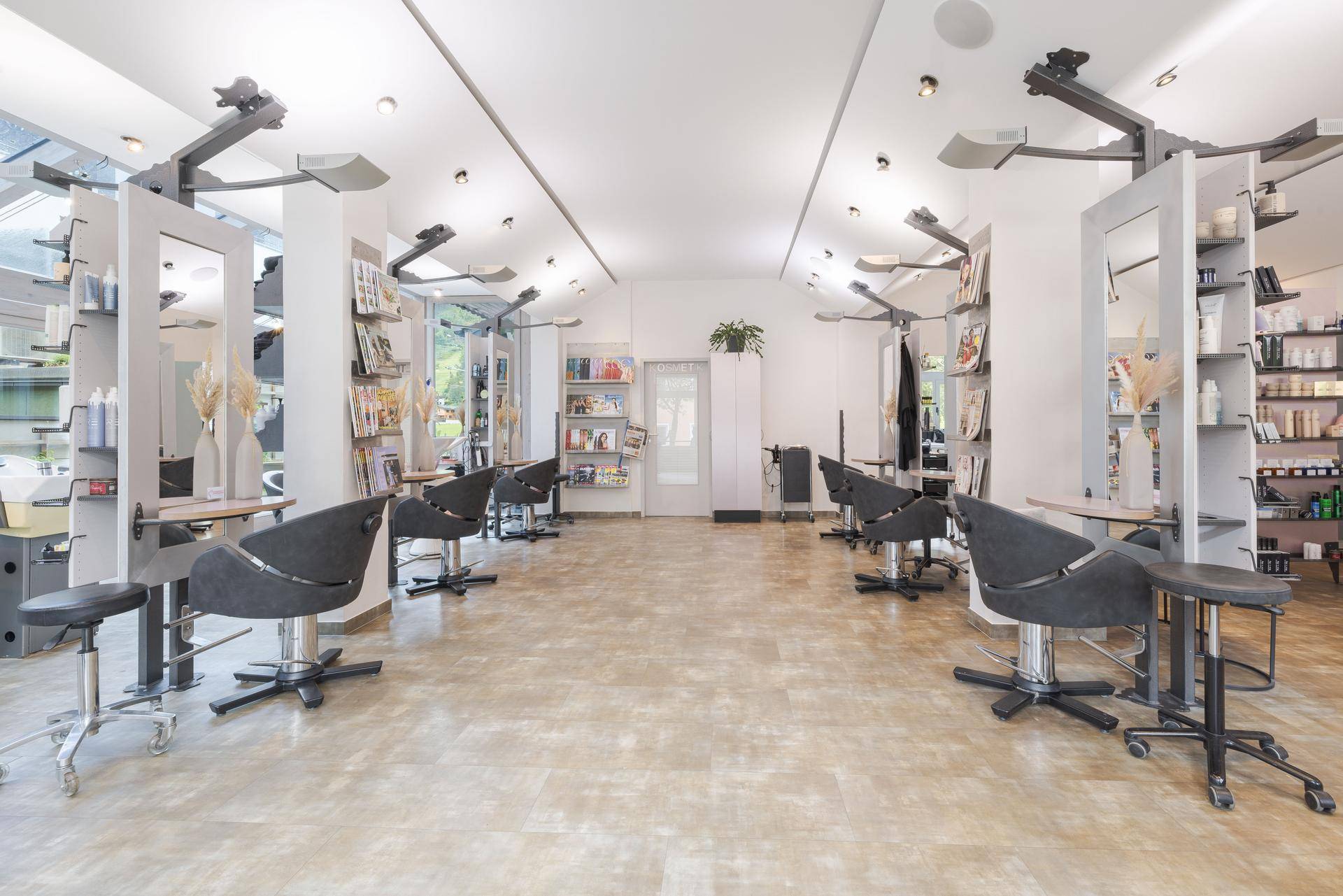 Großer, heller Salon mit vielen Friseurstühlen, Spiegeln und Produktregalen.